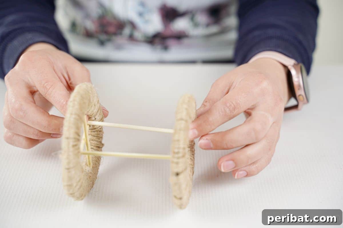 Dowel rods being glued securely between two twine-wrapped wheels, forming the axle.