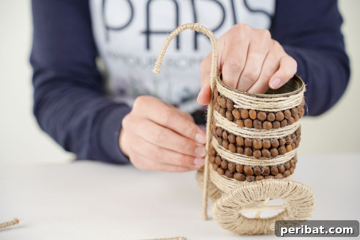 Hands carefully bending a twine-covered floral wire, shaping it into a handle for the vase.