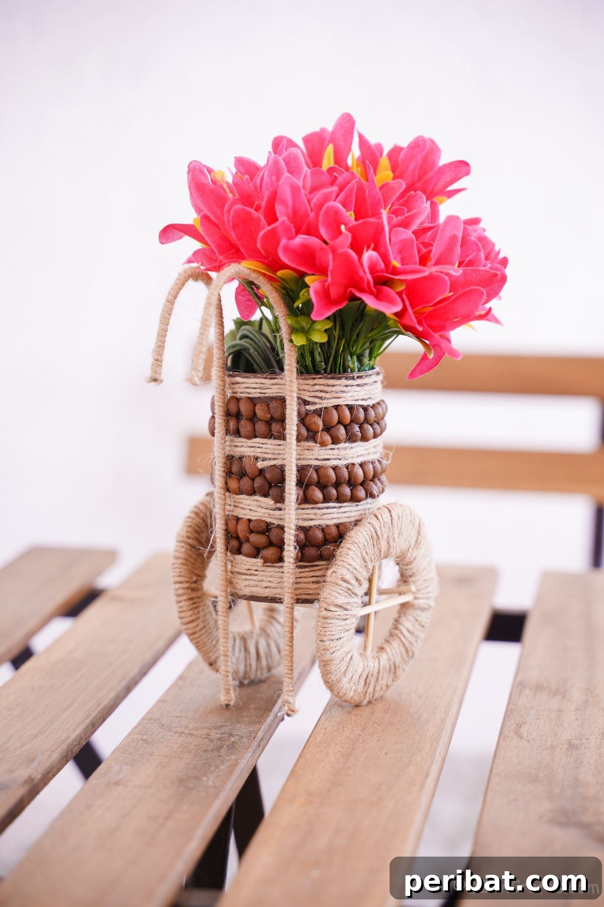 Rustic upcycled vase filled with pink flowers, sitting on a wooden picnic table, ready for display.