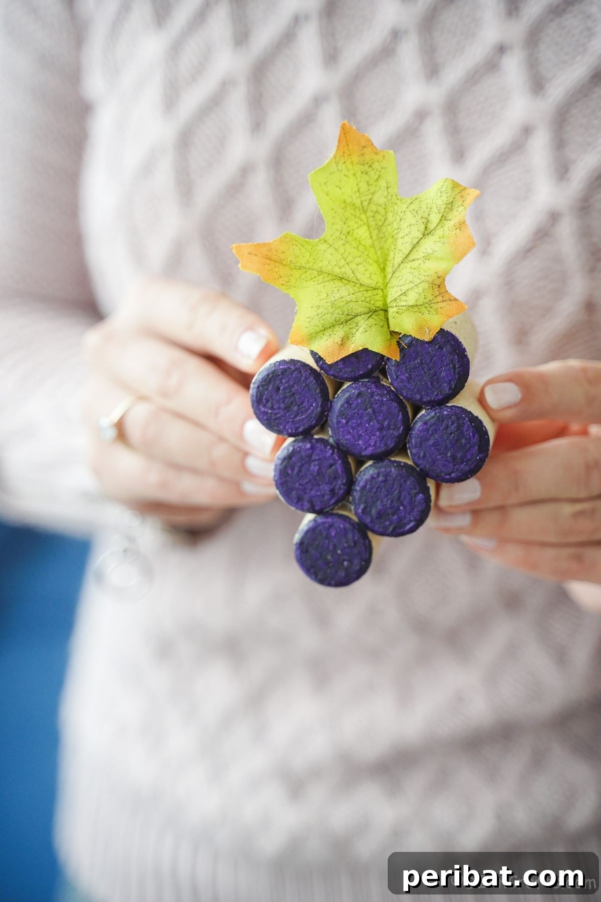 lady in white sweater holding wine cork grape cluster