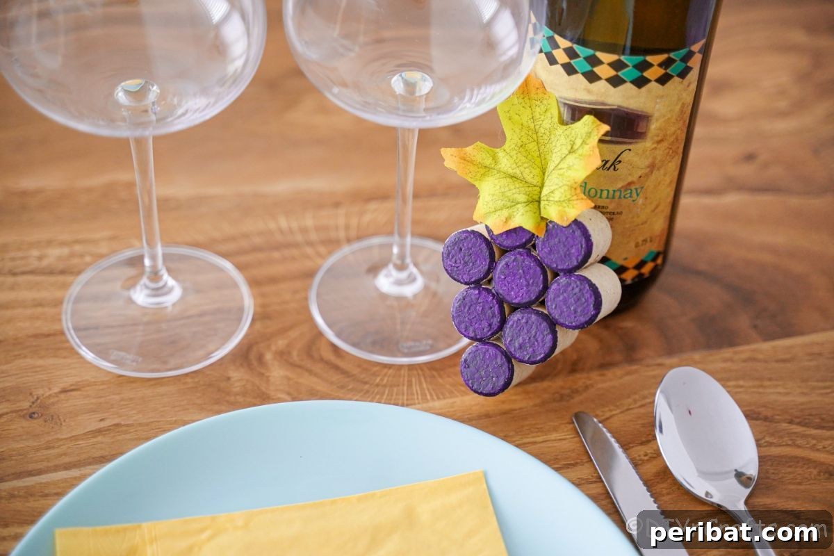 Place setting with two wine glasses, a bottle of wine, and a cork grape cluster.