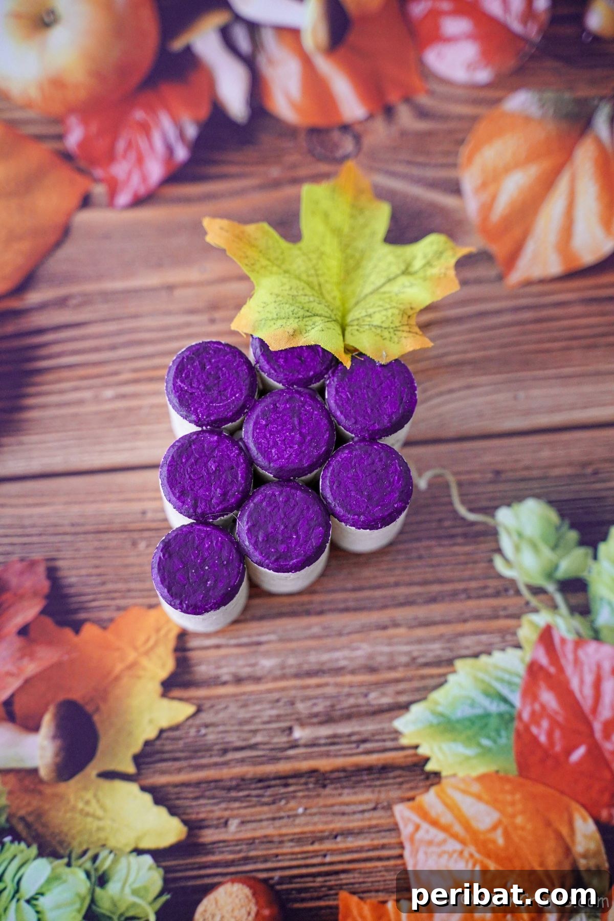 Painted cork grape cluster on a table with artificial leaves, highlighting its decorative appeal.