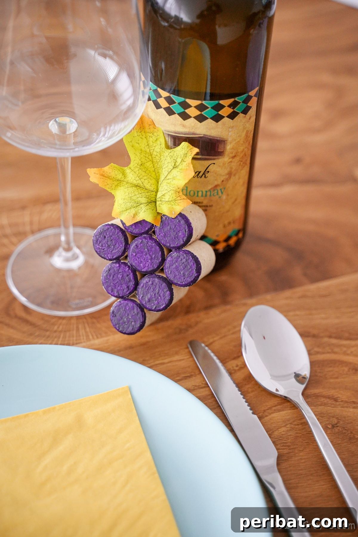 wine cork grape cluster leaned against wine bottle by wine glass at place setting