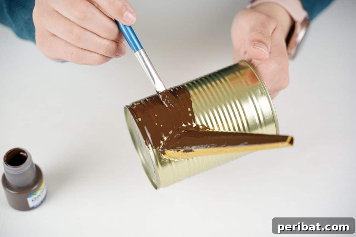 Rustic Coffee Motif Tin Watering Can 16 Hand applying brown craft paint onto the tin can, handle, and spout for a rustic base color