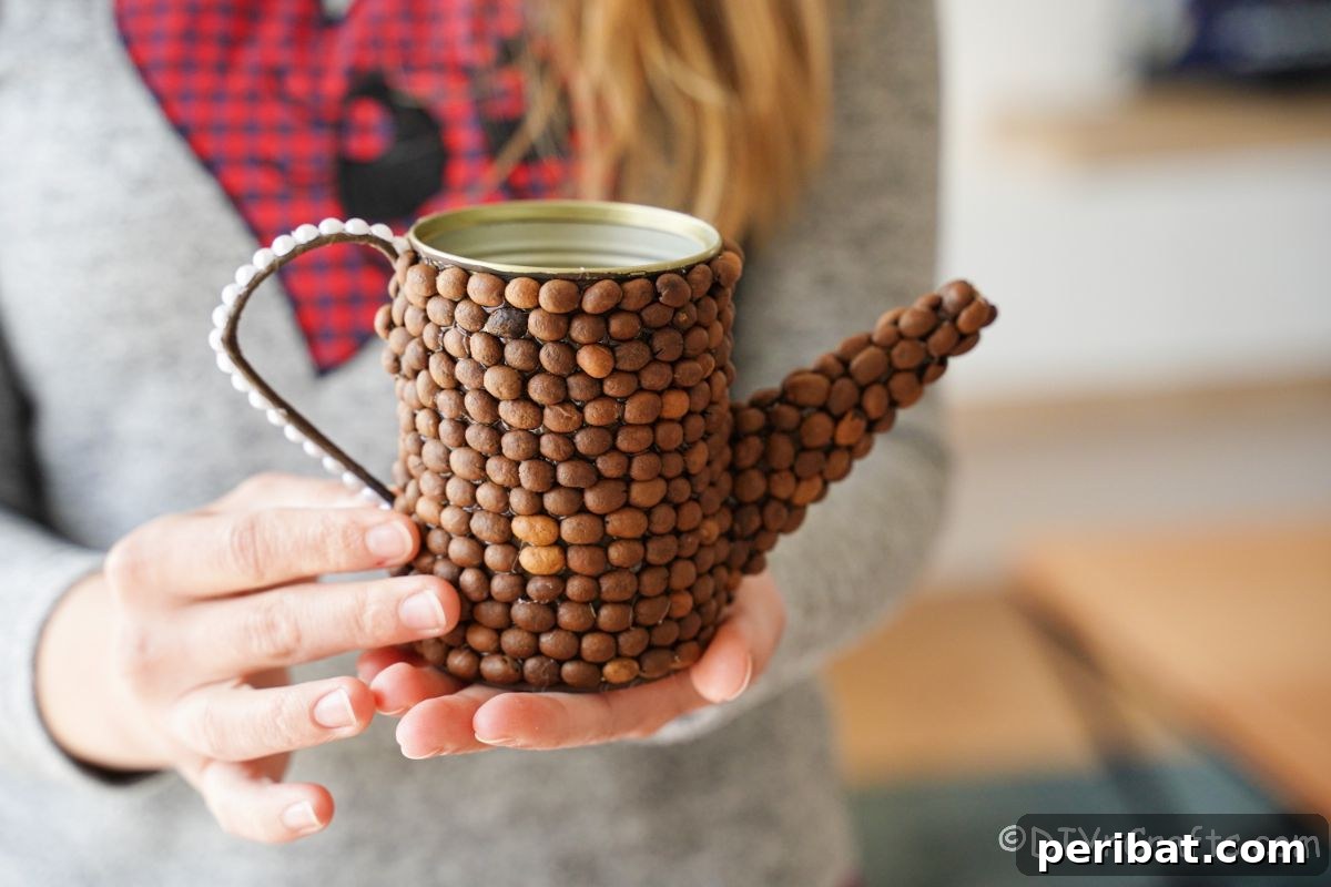 Rustic Coffee Motif Tin Watering Can 21 Finished rustic coffee bean covered watering can held gently in a lady's hand, ready for display