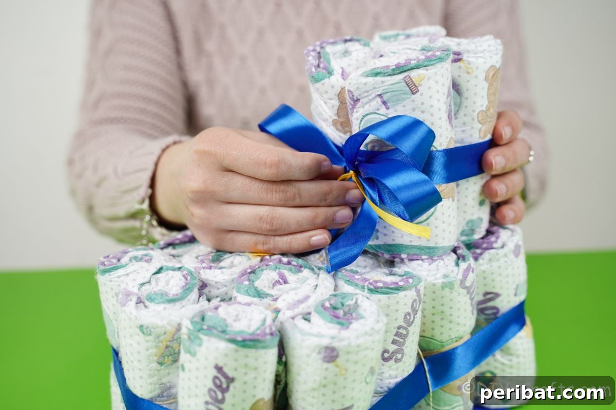 Sweet Steps Diaper Cake Delight 18 hand adding blue bow to front of diaper cake