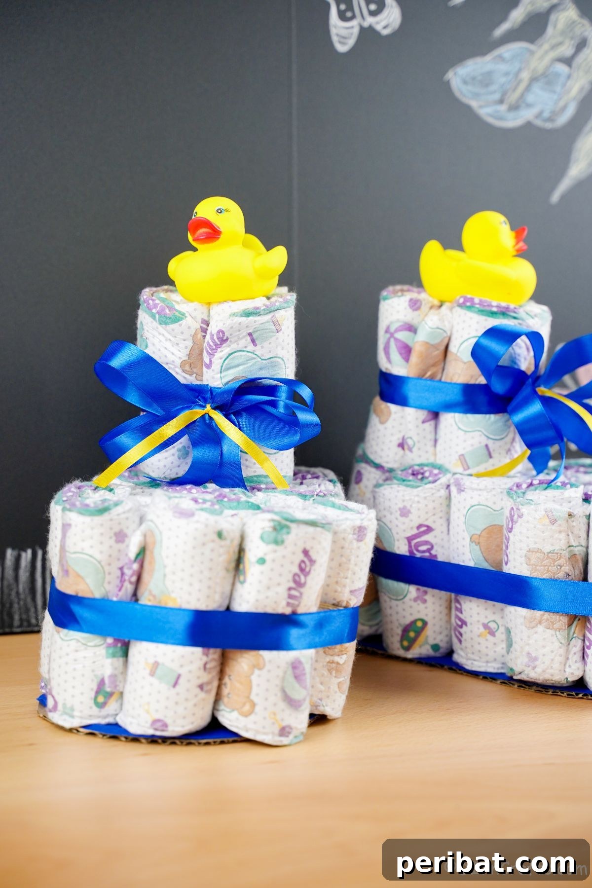 Sweet Steps Diaper Cake Delight 23 baby bootie diaper cakes on table with chalkboard background