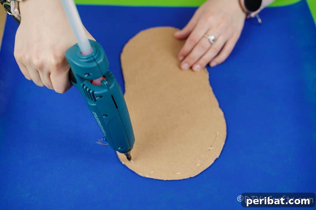 Sweet Steps Diaper Cake Delight 10 blue glue gun adding glue to cardboard shoe shape on top of blue paper