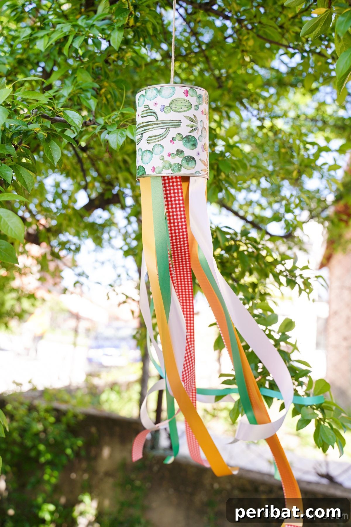 Vibrant Upcycled Tin Can Wind Socks 2 A vibrant tin can windsock adorned with colorful ribbons, hanging gracefully from a tree branch, adding a playful touch to the garden.