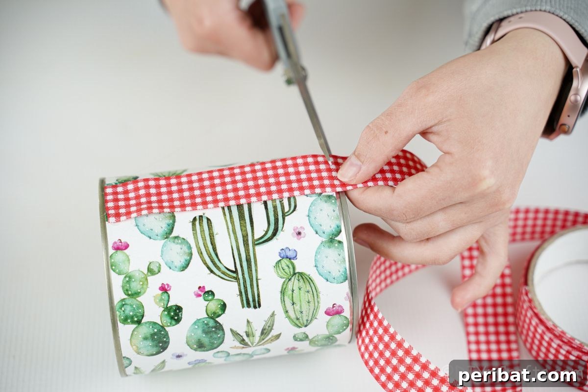 Vibrant Upcycled Tin Can Wind Socks 12 A hand carefully gluing a red and white checked ribbon along the side seam of a decorated tin can, adding a charming decorative accent.