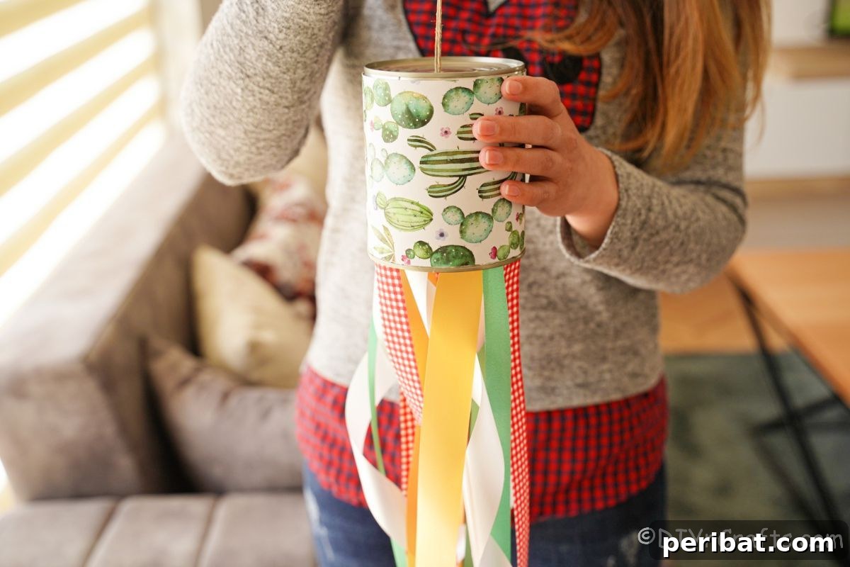 Vibrant Upcycled Tin Can Wind Socks 7 A person holding a finished tin can windsock, showcasing its vibrant ribbons, suggesting the joy of a completed DIY project.