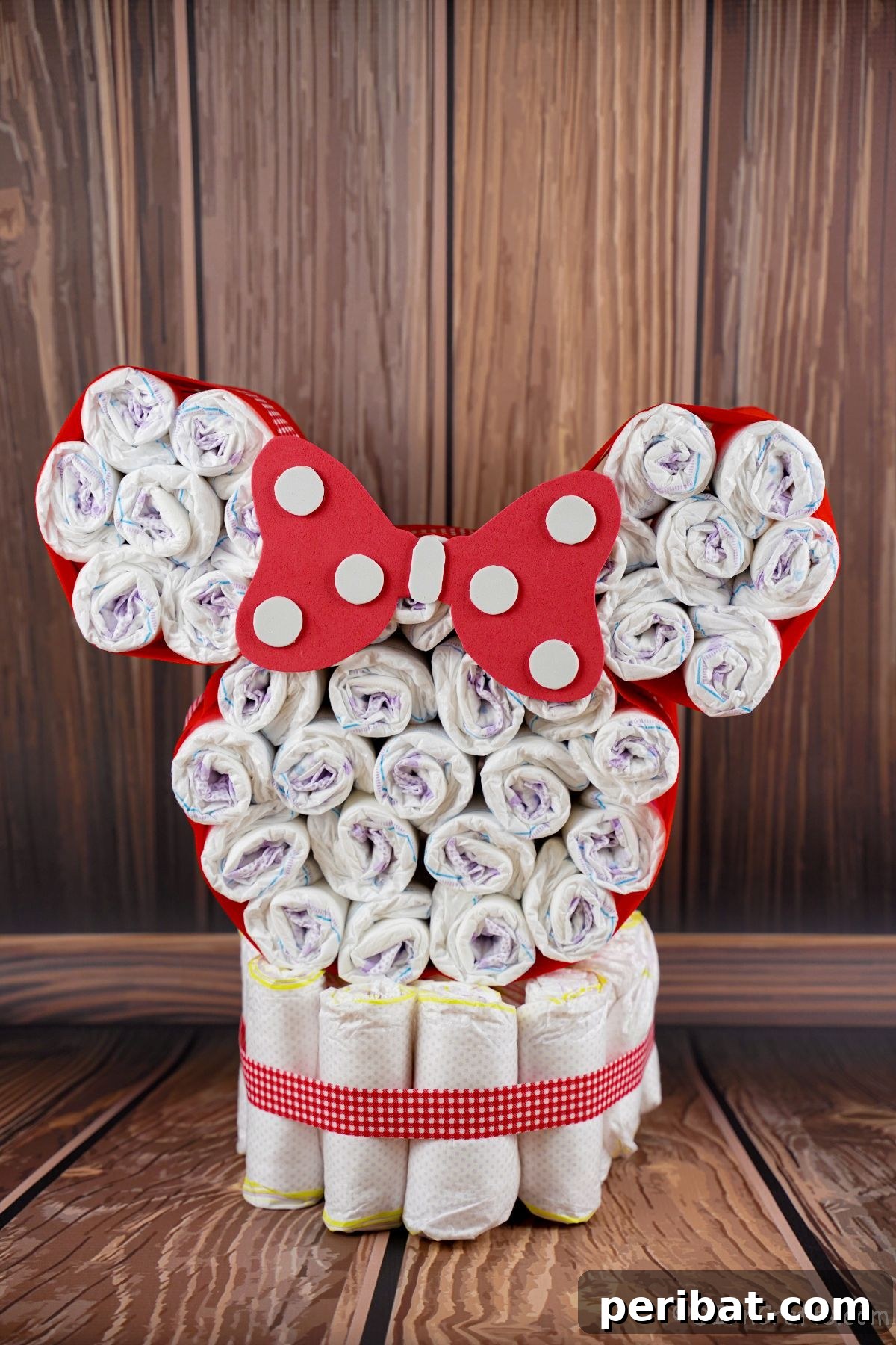 Adorable Disney Minnie Mouse diaper cake sitting on a rustic wooden table, ready for a baby shower.