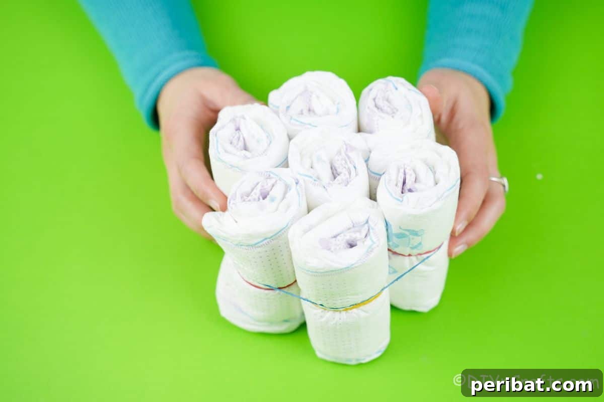 A tightly bound bundle of seven rolled diapers held together by a rubber band, illustrating a component of the cake.