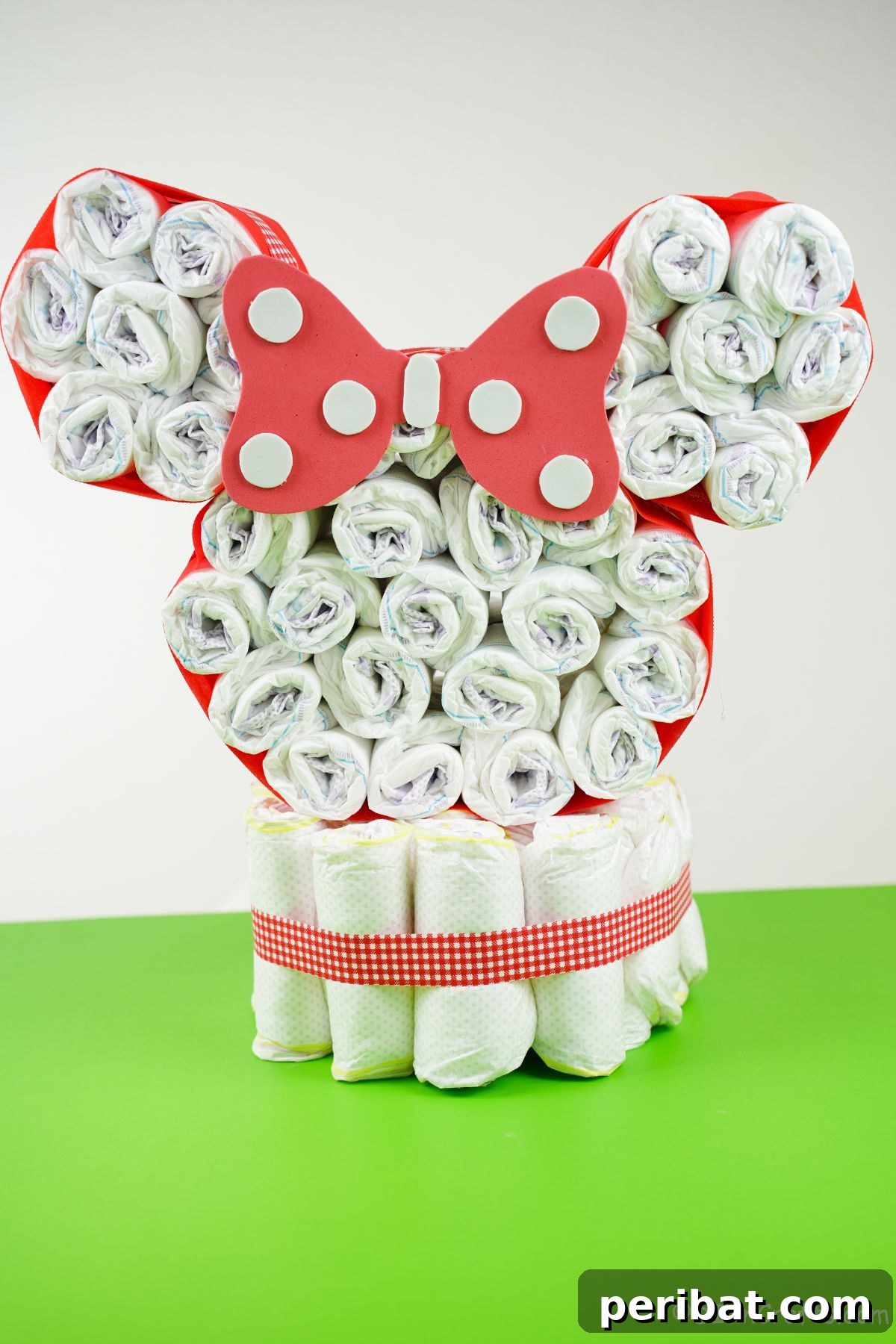 A vibrant green table serving as a backdrop for a completed Disney Minnie Mouse diaper cake, showcasing its festive appeal.
