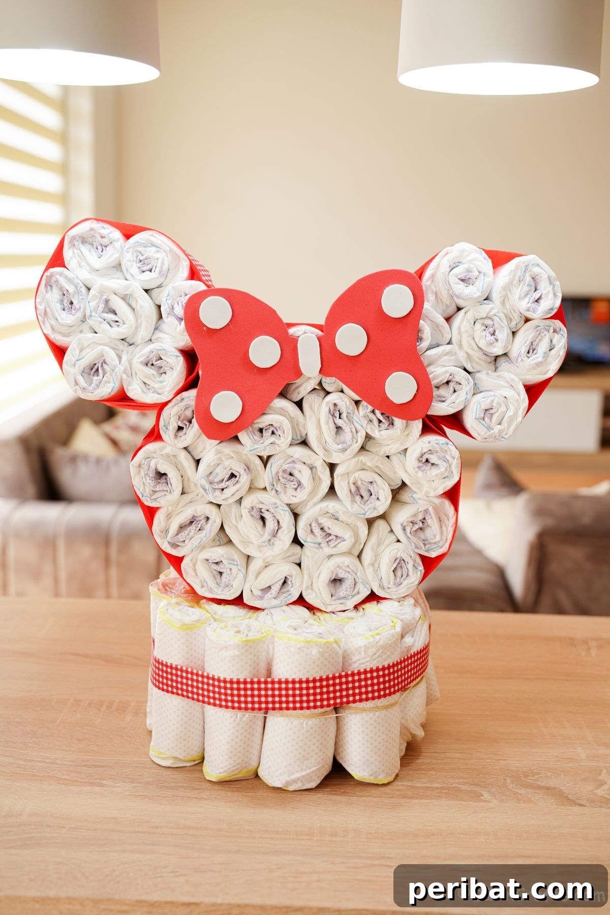 Finished Minnie Mouse diaper cake on a table adorned with festive red and white ribbon, ready for a celebration.