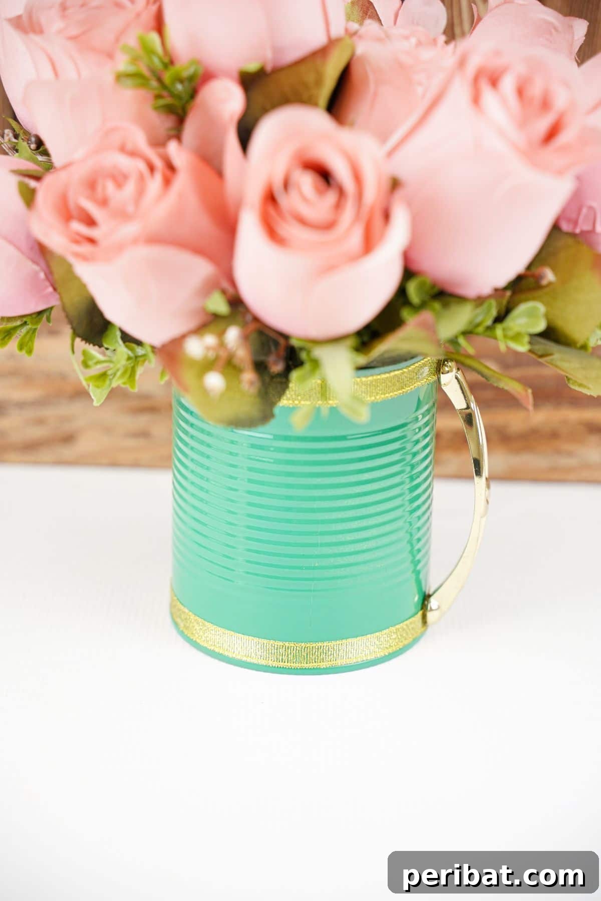 green tin can with gold edge and pink flowers on white table