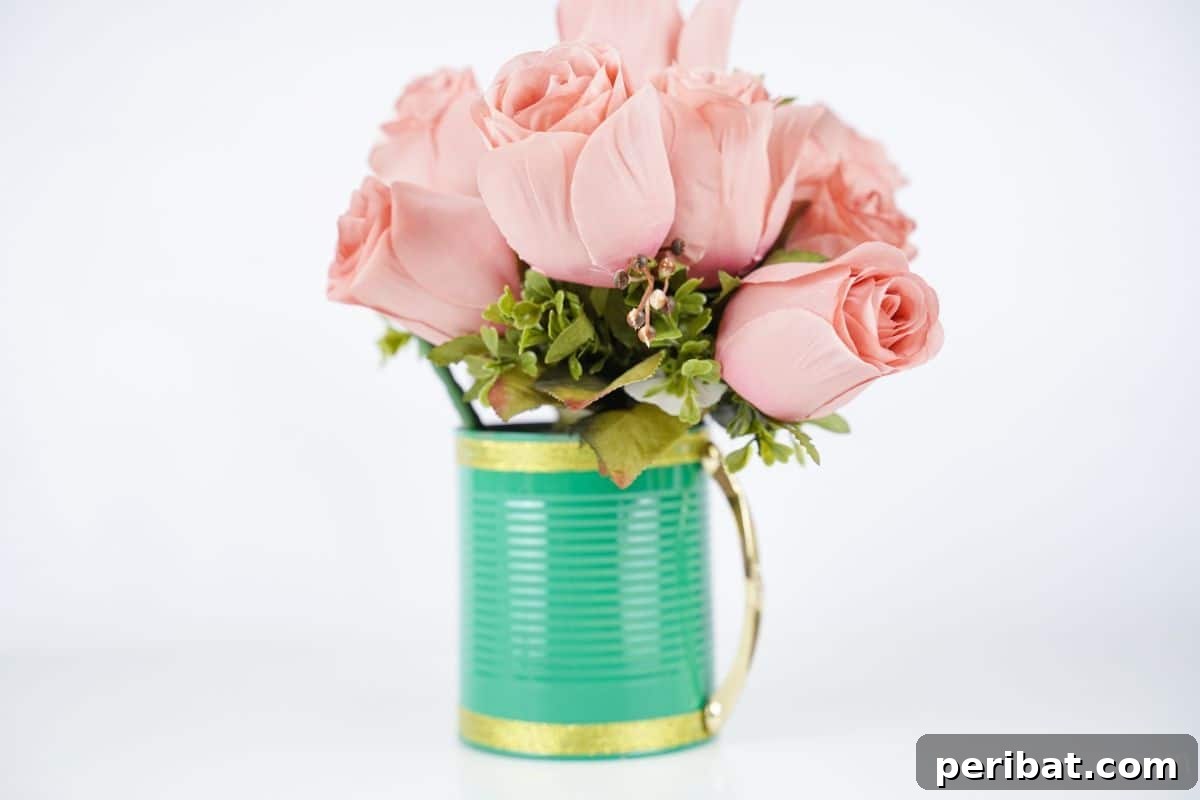 light green and gold tin can with gold handle on white table holding pink roses