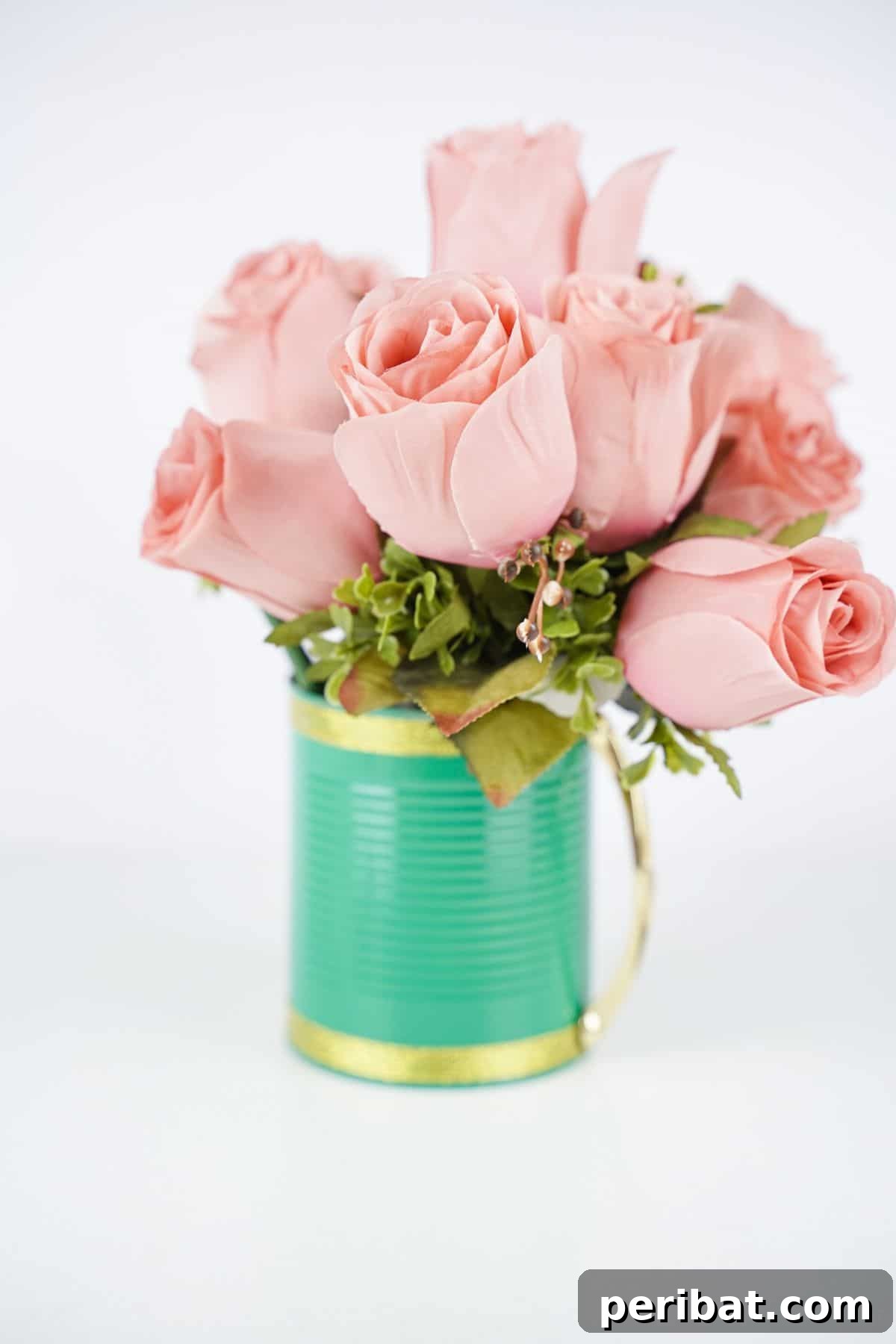 pink roses in light green and gold mug on white table