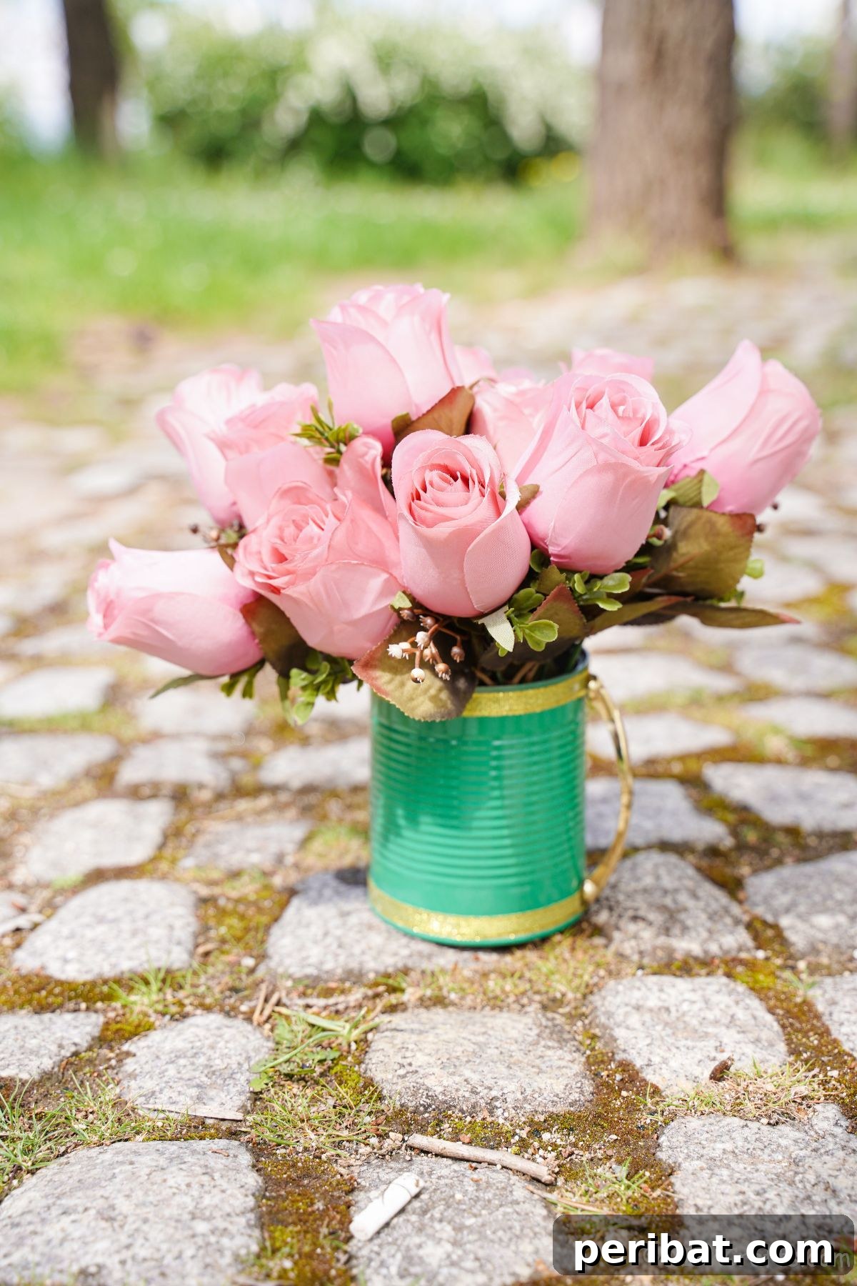 pink roses inside green mug on rock path