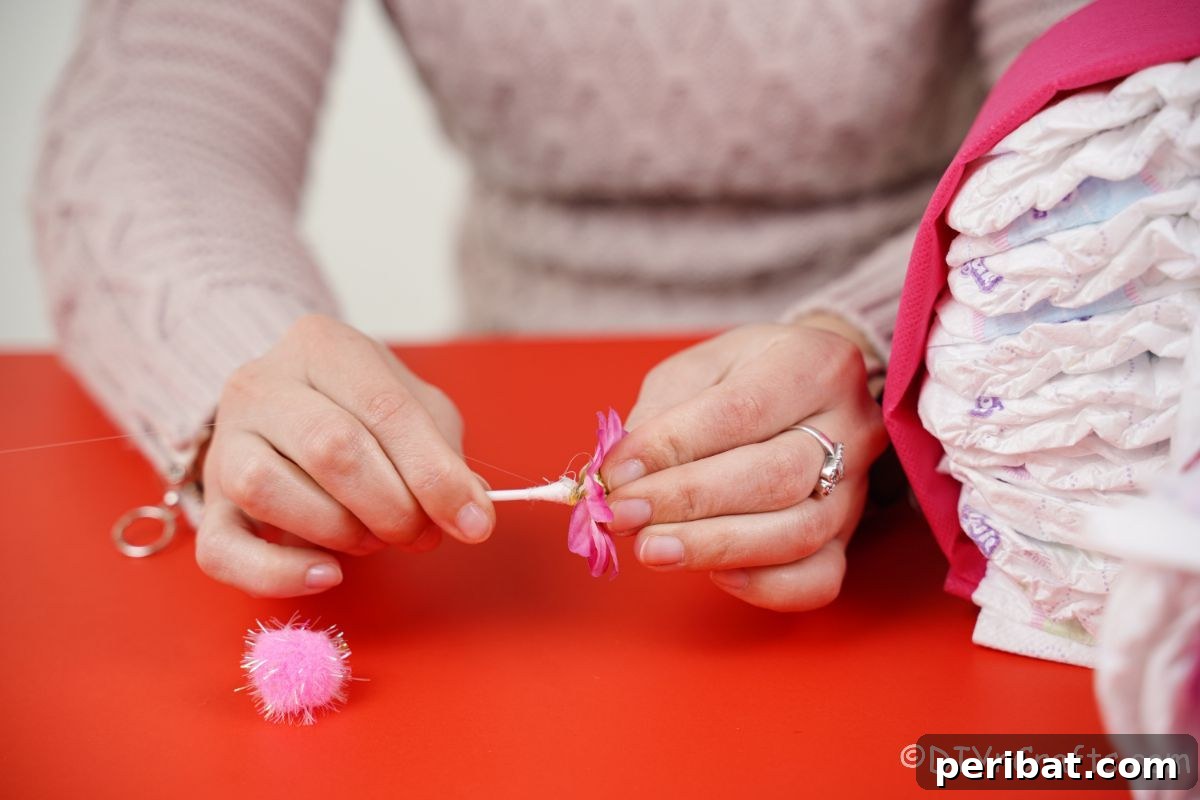 Picture Perfect Diaper Cake Camera 16 Hand gluing a Q-tip to the back of a small fake flower for a camera detail