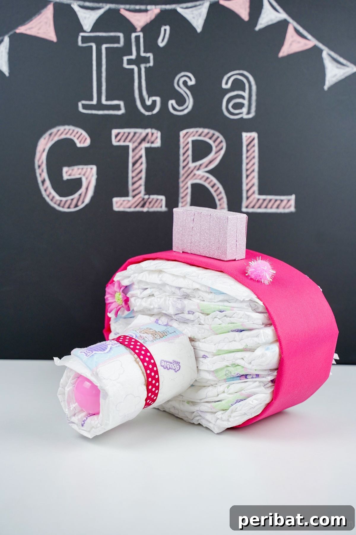 Picture Perfect Diaper Cake Camera 20 Beautifully decorated pink camera diaper cake on a white table with a chalkboard backdrop