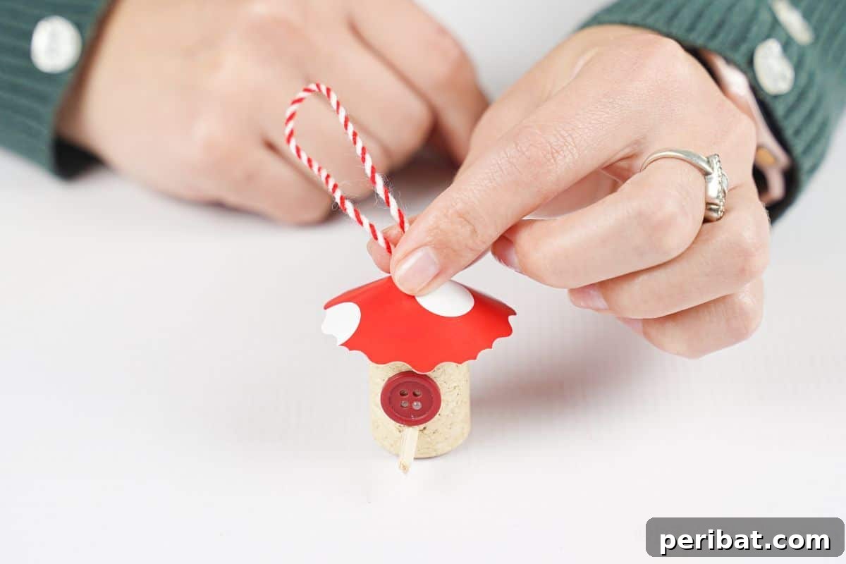 hand holding red and white twine on top of mini birdhouse