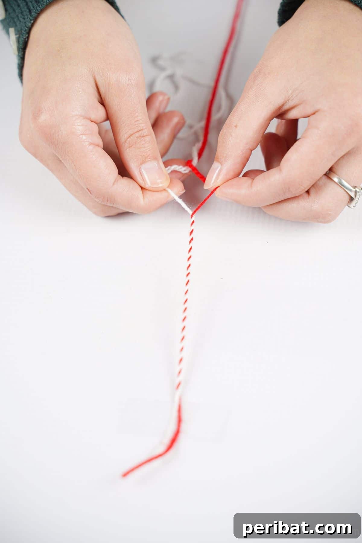 red and white yarn on table being twisted together
