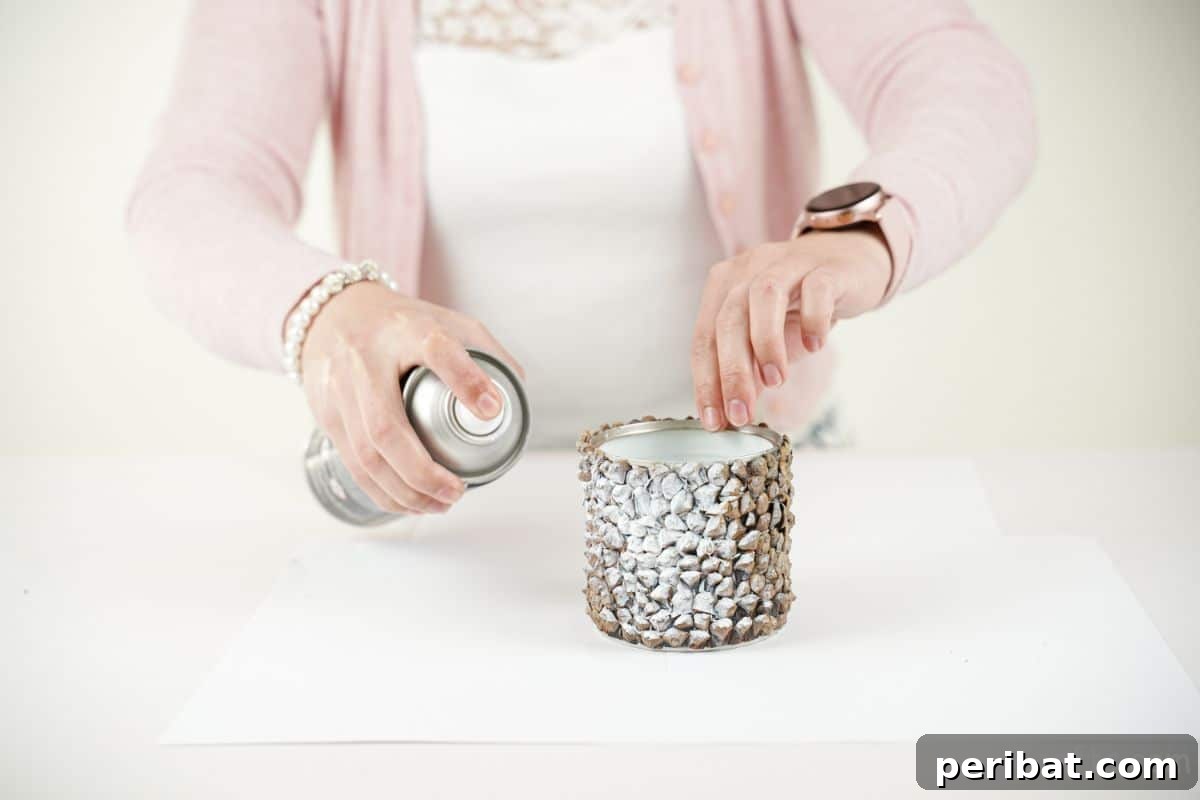 Nature-Inspired Upcycled Tin Can Planters 20 hand holding can and spraying it white