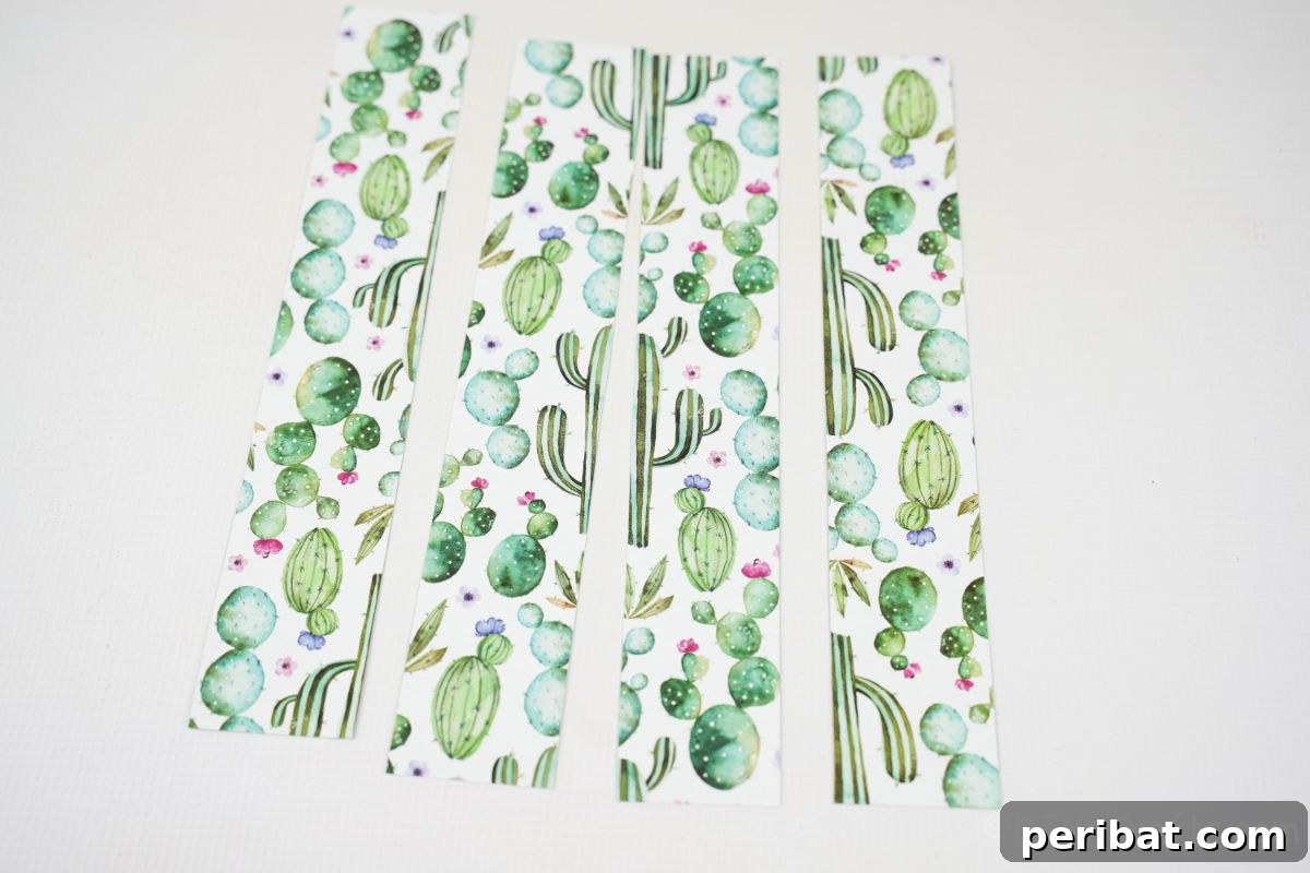Charming Upcycled Tin Door Wreath 12 Four neatly cut strips of white and green cactus-patterned scrapbook paper are arranged on a clean white table, ready for use in a craft project.