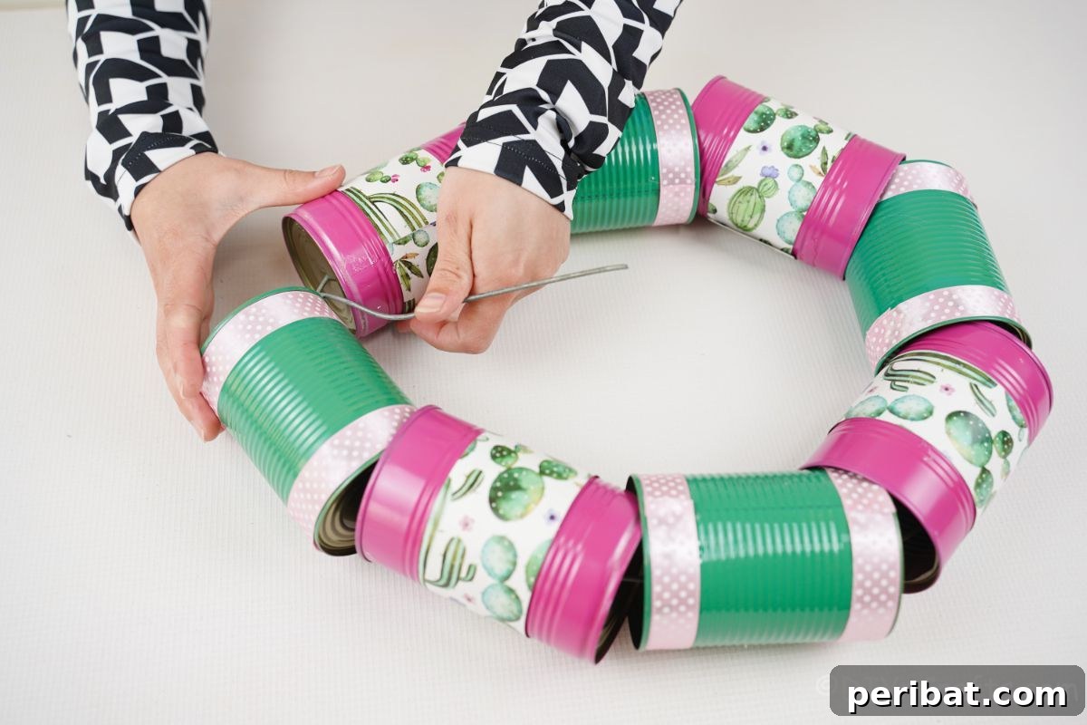 Charming Upcycled Tin Door Wreath 17 Hands are shown carefully attaching the ends of a metal wire together, forming a closed circle with strung tin cans, completing the wreath's base.