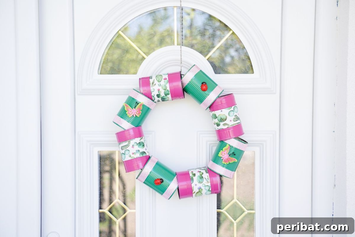 Charming Upcycled Tin Door Wreath 19 A colorful green and pink tin can wreath is prominently displayed on the center of a white front door, adding a cheerful accent to the home's entrance.