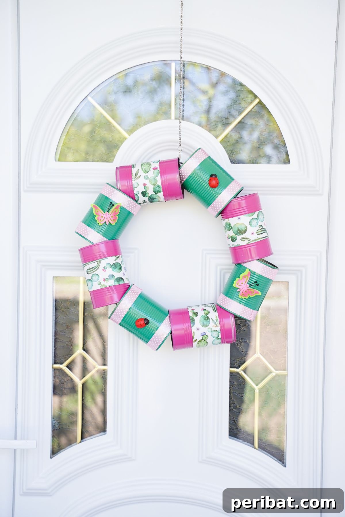 Charming Upcycled Tin Door Wreath 3 Colorful green and pink tin can wreath hanging on a white front door with elegant glass panels, showcasing vibrant spring or summer decor.