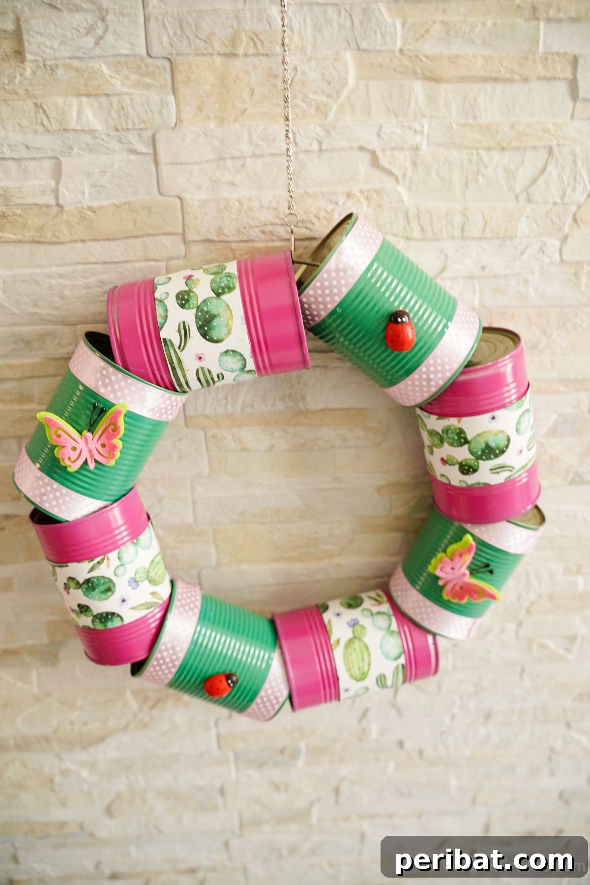 Charming Upcycled Tin Door Wreath 20 A vibrant pink and green wreath, creatively crafted from tin cans, hangs against a textured brick wall, adding a cheerful and unique decoration.
