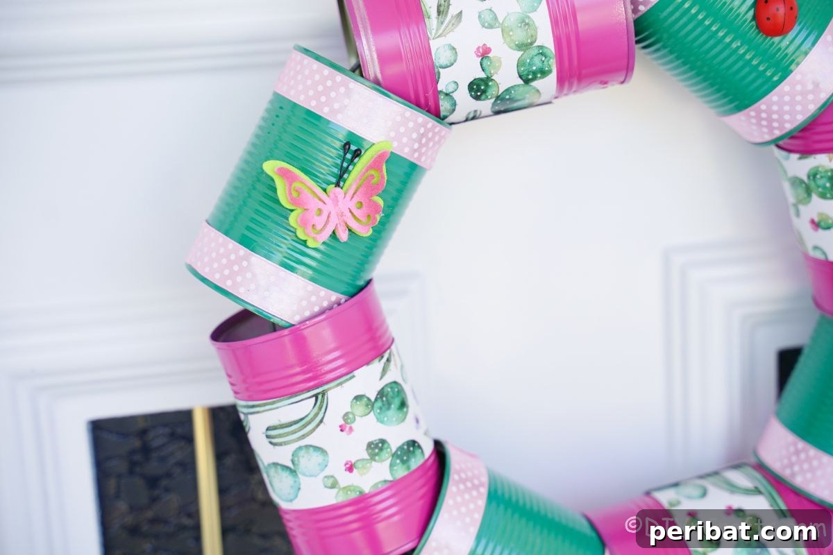Charming Upcycled Tin Door Wreath 7 A beautifully crafted tin can wreath, in shades of pink and green, hangs against a clean white door next to a glass panel, offering a charming welcome.