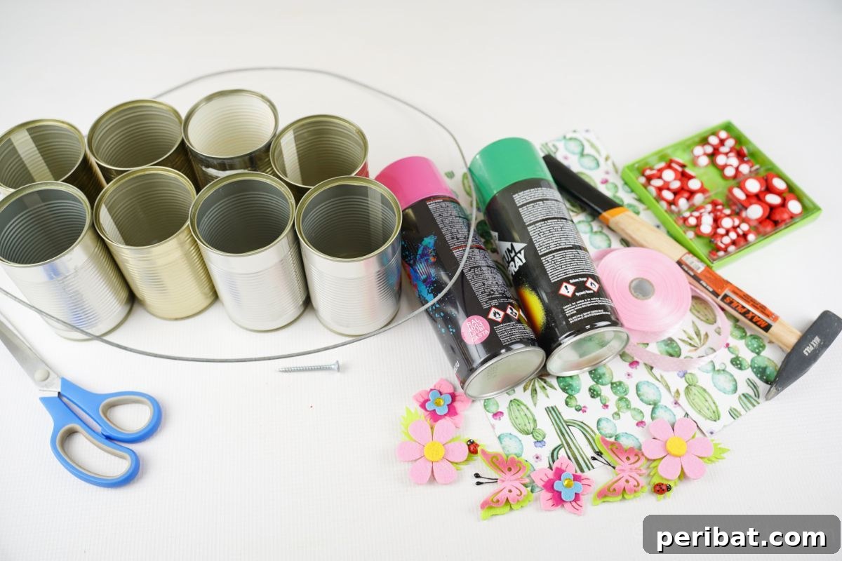 Charming Upcycled Tin Door Wreath 8 Assortment of craft supplies including empty tin cans, pink and green spray paint, patterned scrapbook paper, and a hot glue gun arranged on a clean white table.