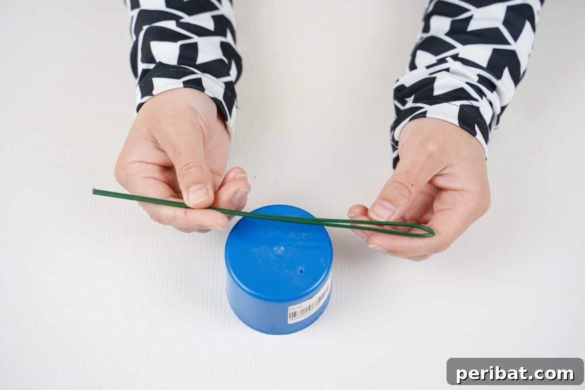hand wrapping green wire around blue paint can cap