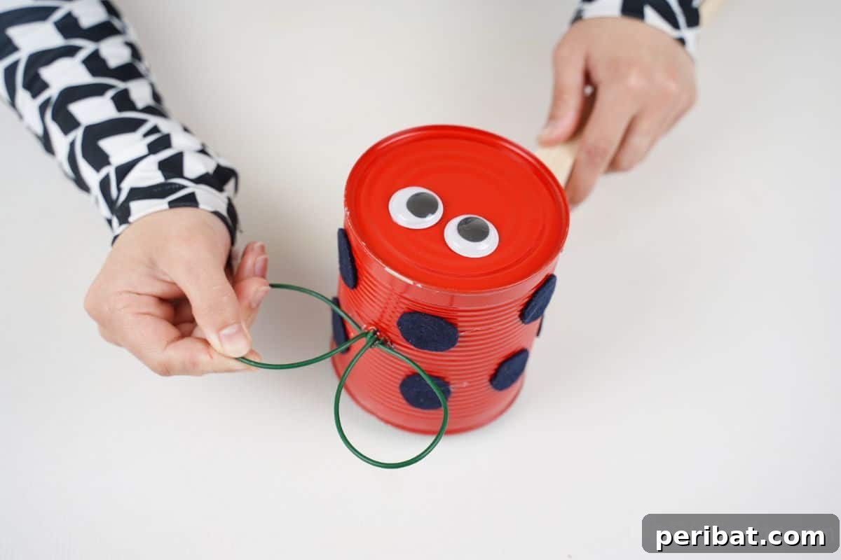 hand gluing wings on top of ladybug