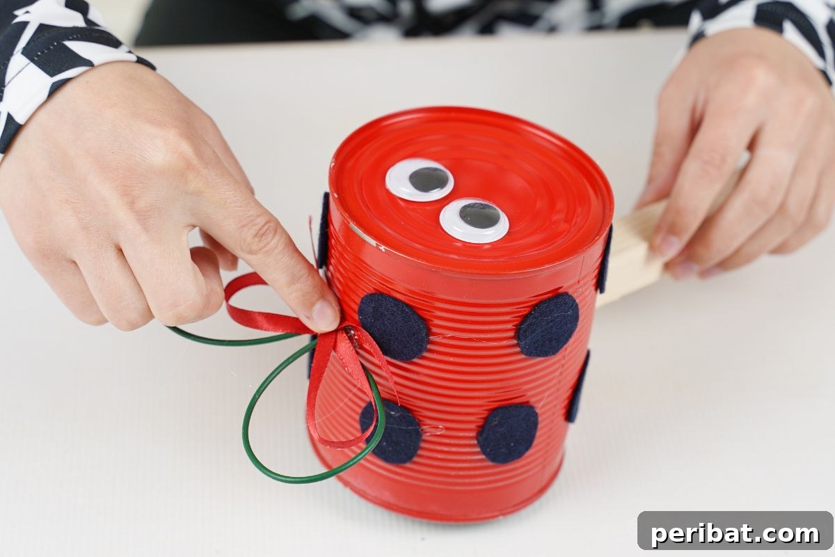 hand gluing bow on top of ladybug tin can