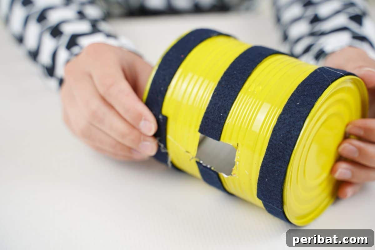 hand holding black paper around yellow ladybug tin can