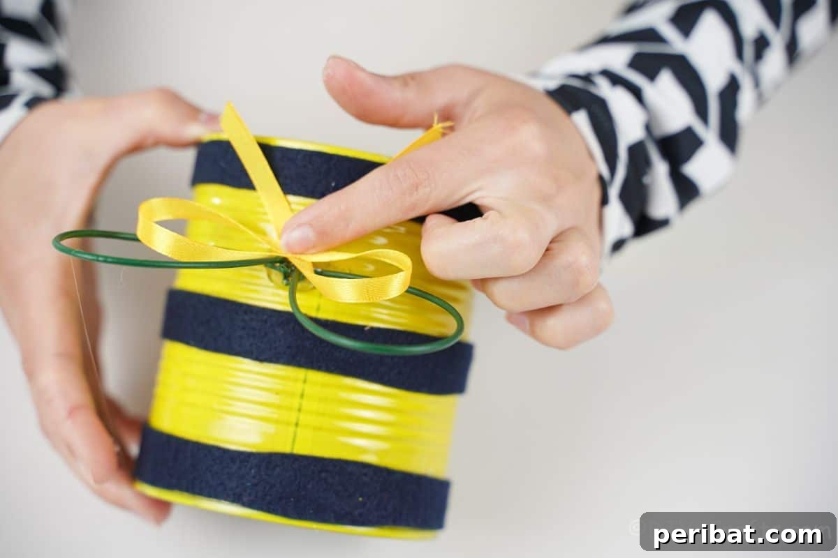 hand tying yellow ribbon on top of tin can bee
