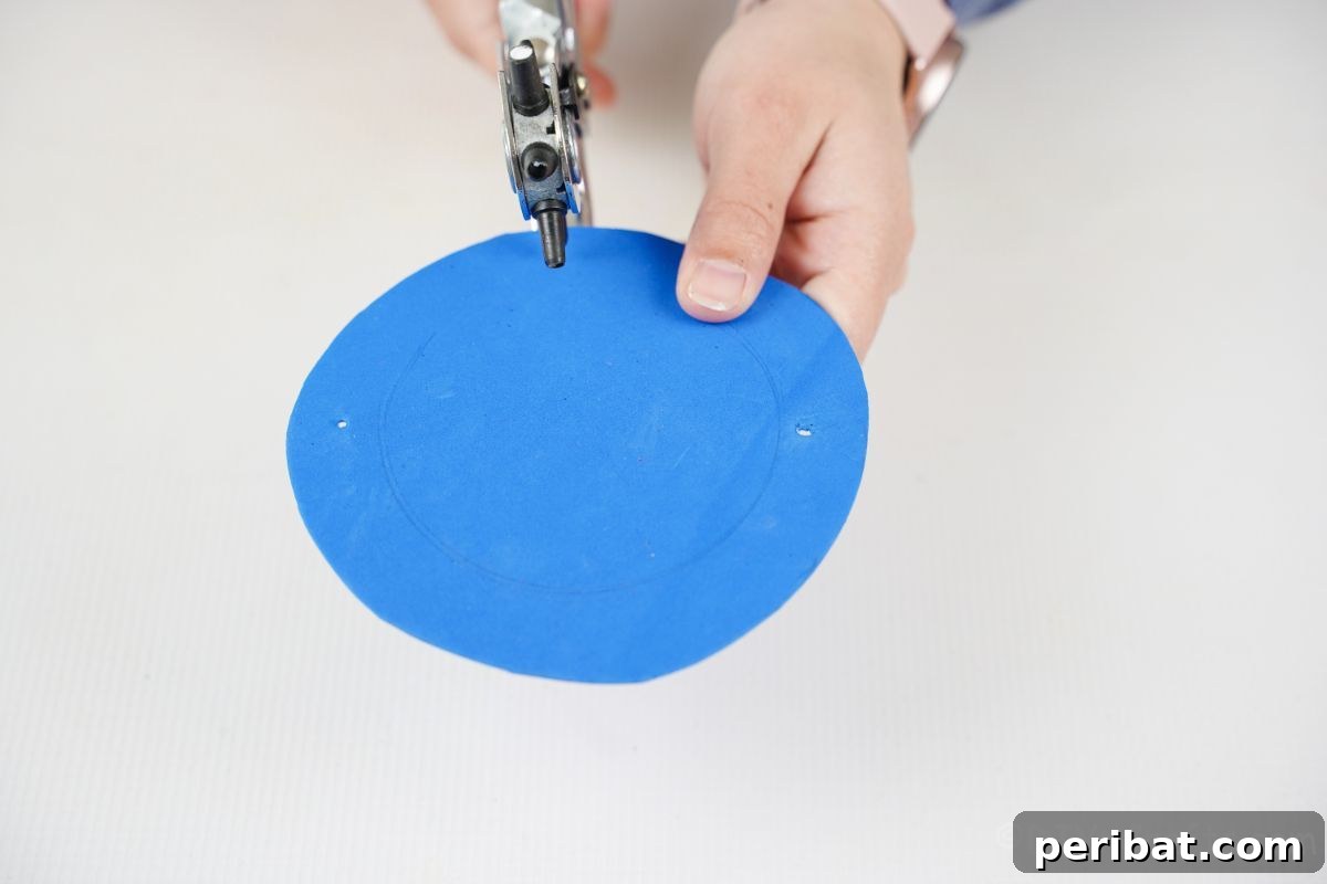 Percussion from the Pantry: Upcycled Tin Can Drums 11 blue foam paper circle being cut with hole punch