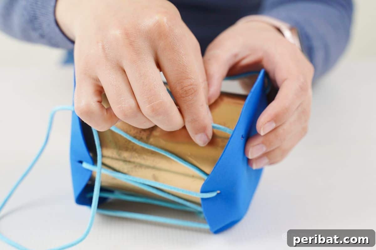 Percussion from the Pantry: Upcycled Tin Can Drums 12 hands threading blue leather ribbon through holes on blue foam on top of gold tin can
