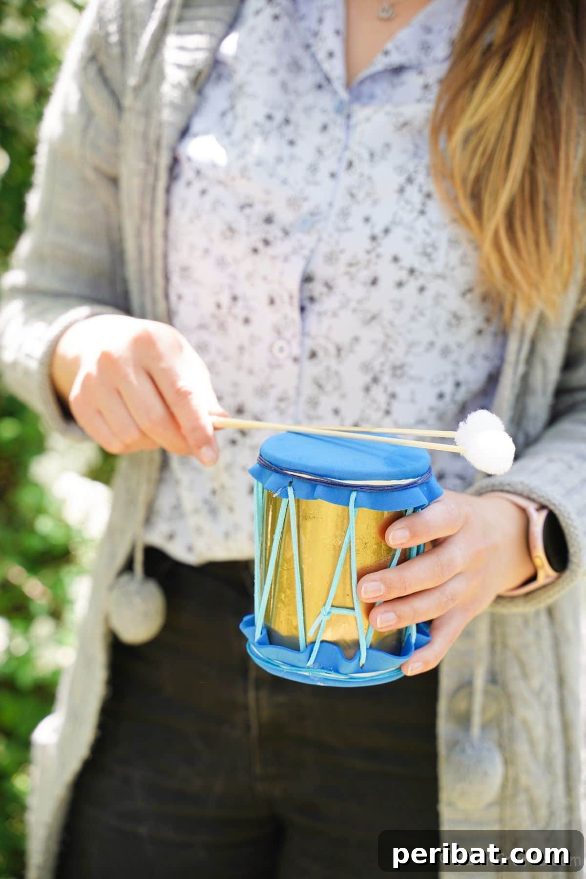 Percussion from the Pantry: Upcycled Tin Can Drums 16 tin can drum with gold and blue accents being held by woman in black pants