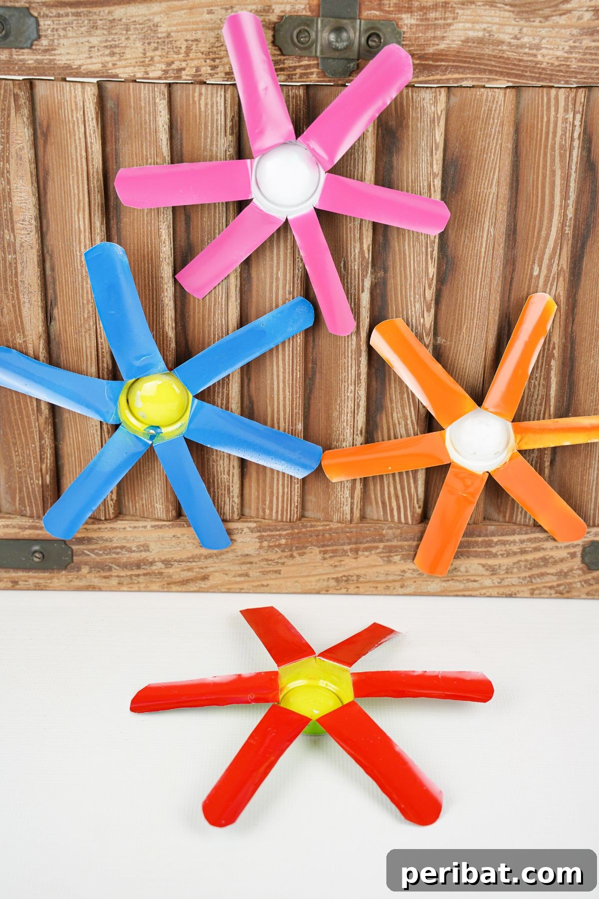 Aluminum Bloom Art 4 soda can flowers against wood wall and white floor
