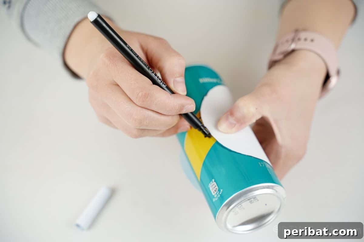 hand tracing onto soda can with black marker