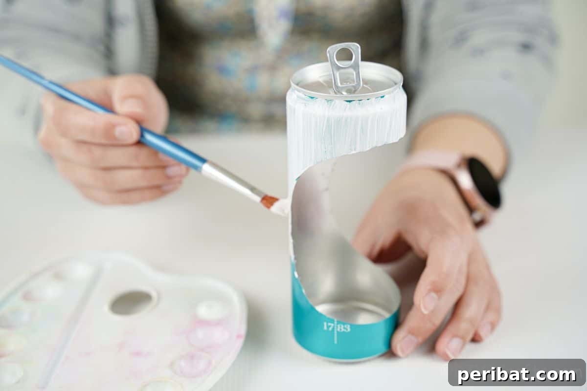 hand holding blue paintbrush against soda can