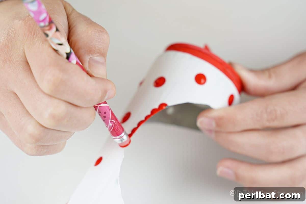 hand holding pencil to paint red dots around white can