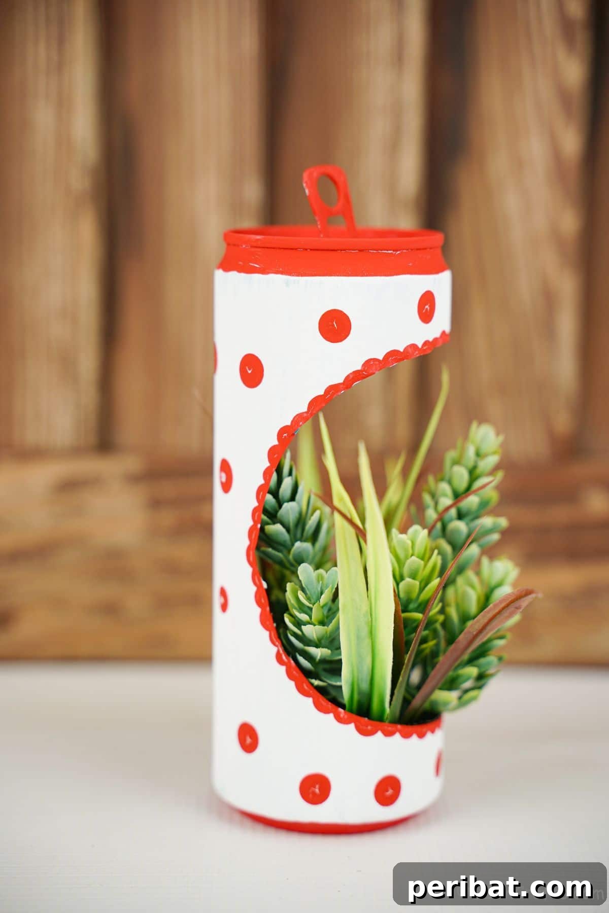 white soda can with red dots as a succulent planter on table with wood background