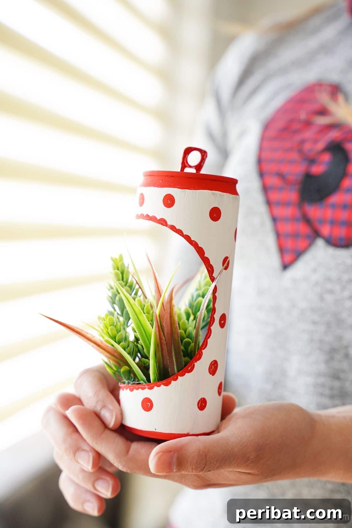 woman holding soda can planter in front of window
