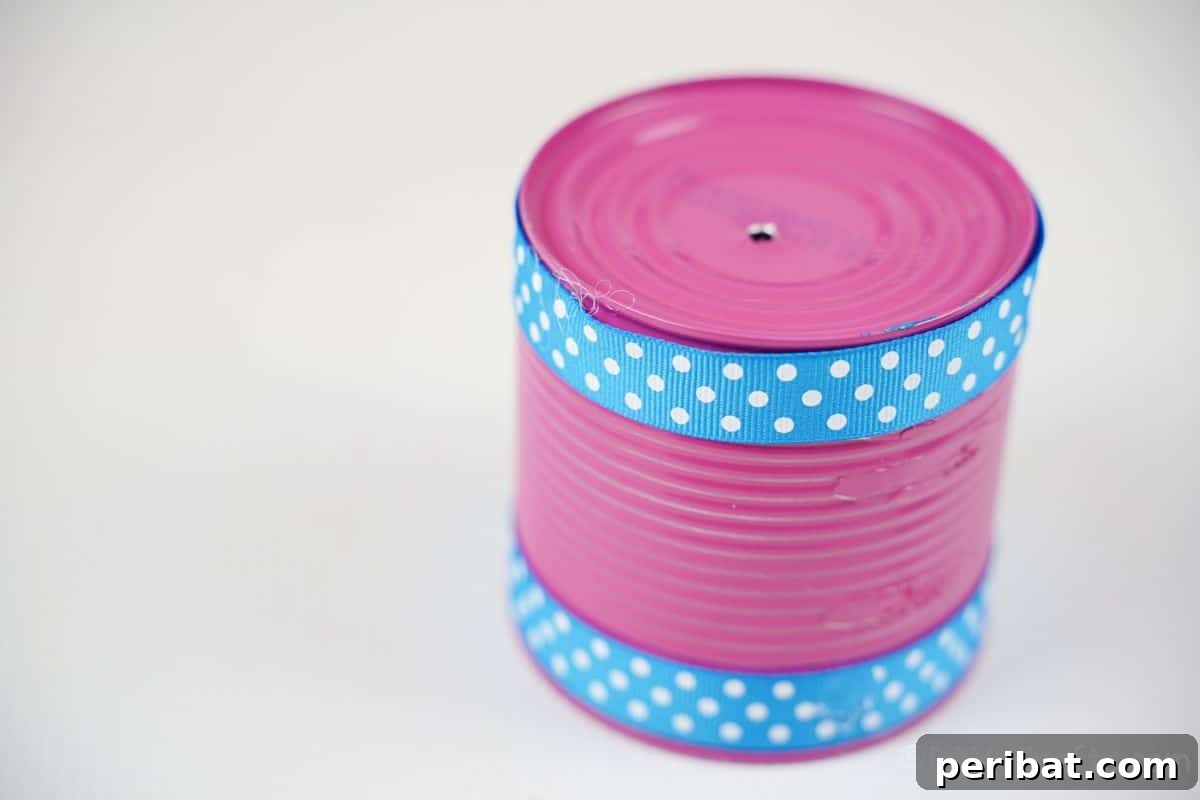 Transform Tin Cans into Melodious Wind Chimes 13 A vibrant pink tin can elegantly decorated with a contrasting blue polka dot ribbon, adding a charming visual touch